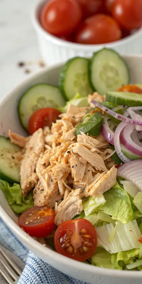 Hot chicken salad with colorful vegetables and spicy shredded chicken in a white bowl