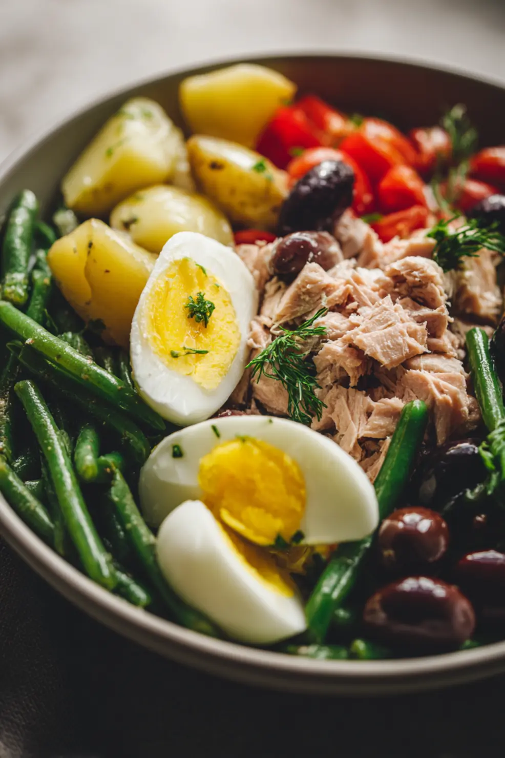 Close-up of a portion of Niçoise salad showing tuna, potatoes, and green beans with dressing