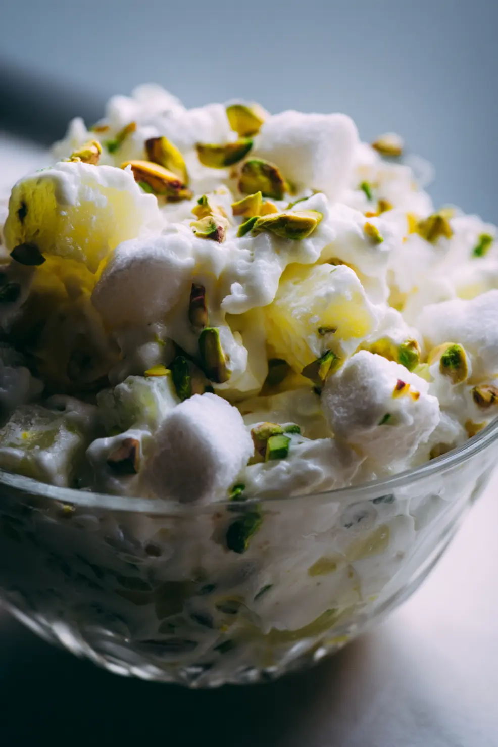 Watergate salad recipe in a serving bowl garnished with pistachios and cherries
