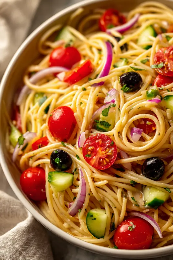 California Spaghetti Salad served in a white bowl garnished with fresh herbs