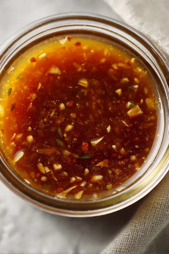 Homemade Catalina Salad Dressing in a glass jar with fresh ingredients surrounding it