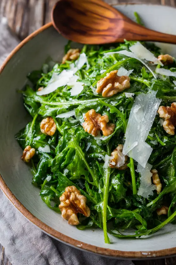 A beautifully plated dandelion salad with walnuts and Parmesan shavings