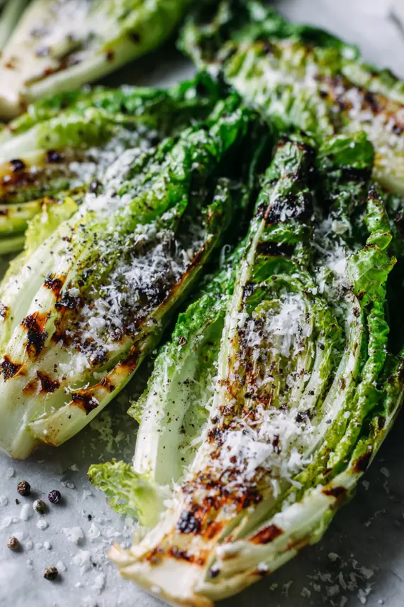 Beautifully plated grilled romaine salad with Parmesan and lemon garnish on a serving platter