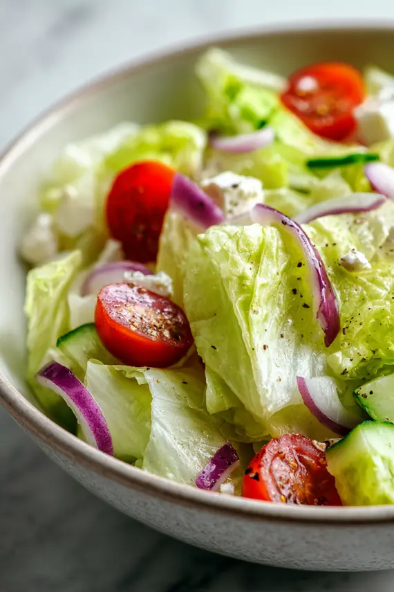Finished iceberg lettuce salad in a white bowl garnished with fresh herbs