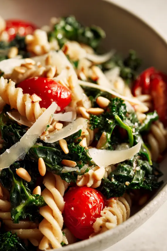Kale pasta salad served in a white bowl with fork on the side