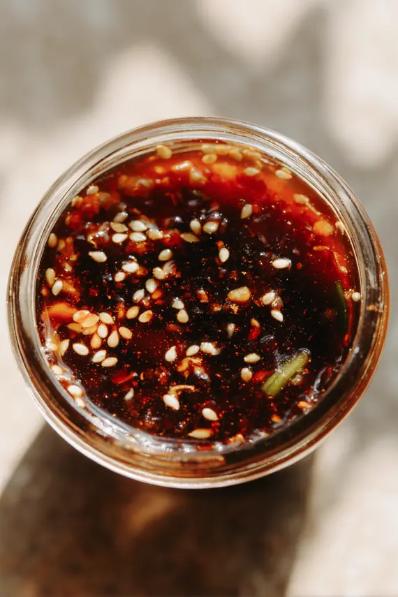 Korean salad dressing in a glass jar with vegetables in the background