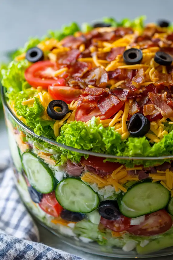 Beautifully layered seven layer salad in a glass trifle bowl