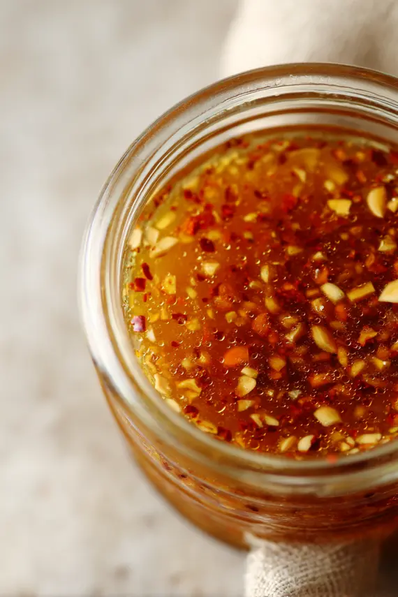 Bowl of vibrant thai salad dressing with crushed peanuts and Thai chilies