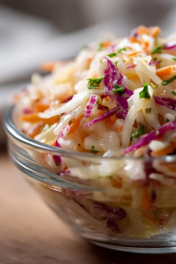 Sauerkraut salad served in a white bowl with fresh herbs garnish